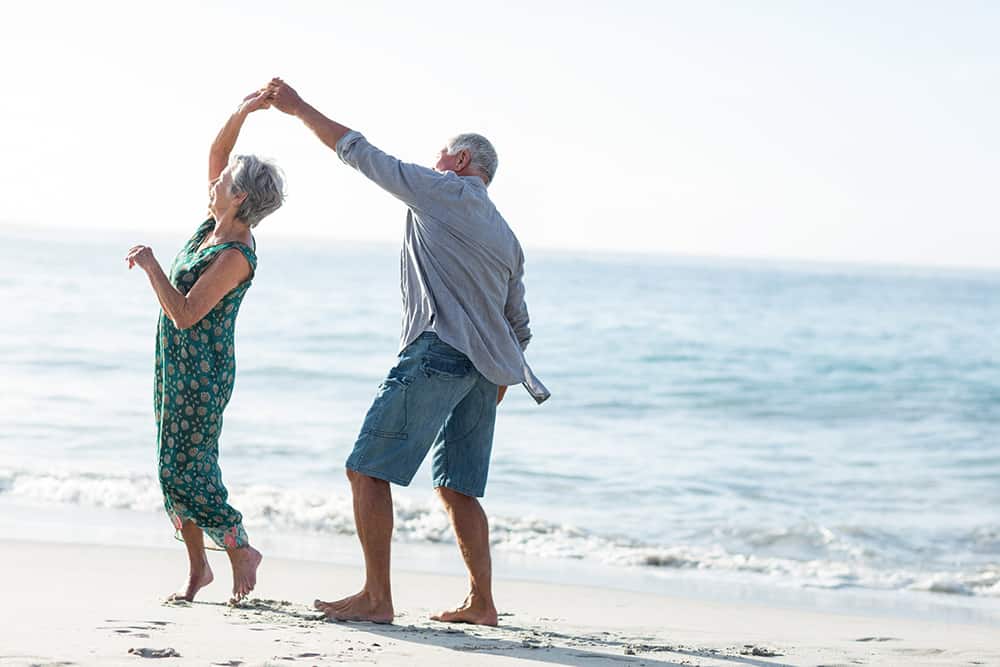 A senior couple dancing together happily on a beach