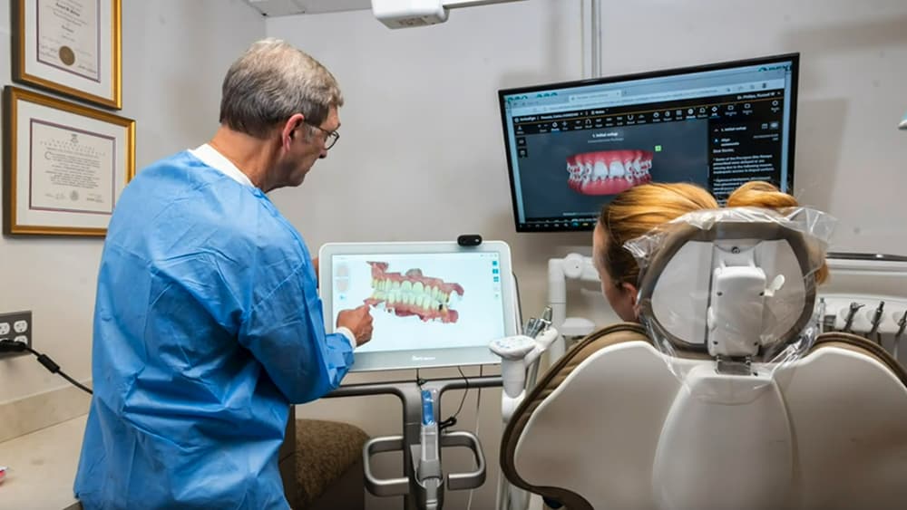 Dr. Phillips using a dental scanner device to create a 3D model of the patient's teeth and gums